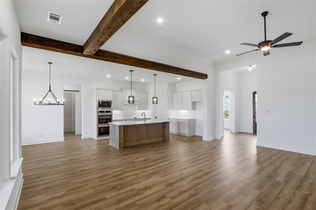 810 Vly Rdg Road Van Alstyne, TX 75495 - Photo 38 of 39 Kitchen featuring open floor plan, a kitchen island with sink, beam ceiling, a ceiling fan, and light wood-type flooring