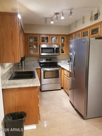 a kitchen with stainless steel appliances granite countertop a refrigerator a stove and a sink