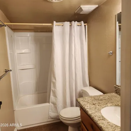 a bathroom with a granite countertop sink toilet and shower