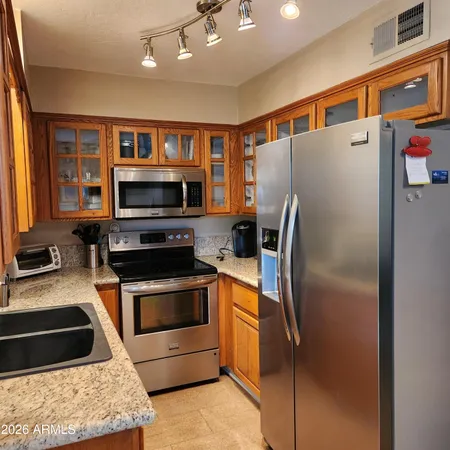 a kitchen with stainless steel appliances granite countertop a refrigerator a stove and a sink with wooden floor