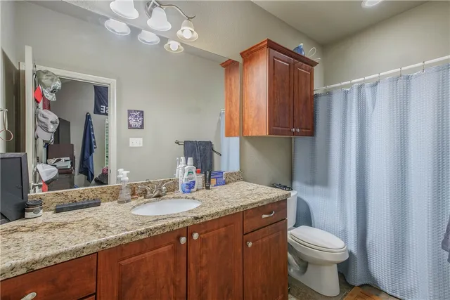 a bathroom with a granite countertop sink a toilet and a mirror