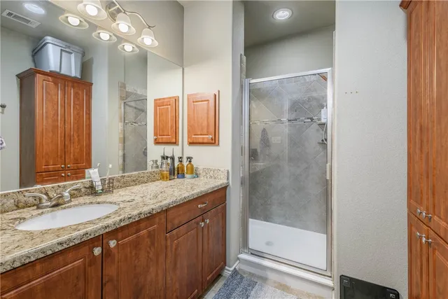 a bathroom with a granite countertop sink a mirror and a shower