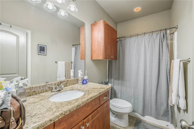 a bathroom with a granite countertop sink toilet and shower