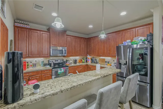 a kitchen with stainless steel appliances granite countertop a refrigerator a sink a stove a dining table and chairs with wooden floor