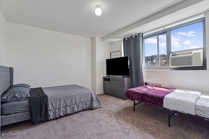 90 Prospect Avenue Hackensack, NJ 07601 - Photo 9 of 21 a bedroom with a bed and a flat screen tv