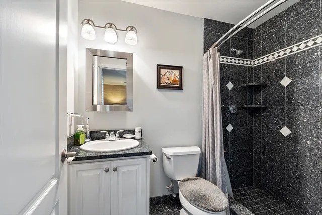 a bathroom with a granite countertop sink toilet and shower