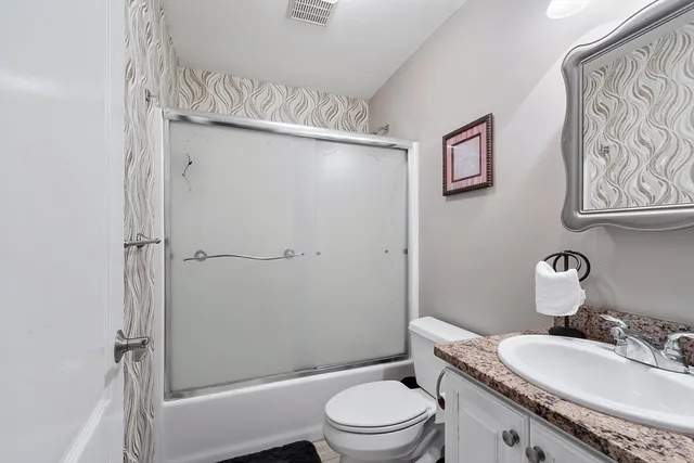 a bathroom with a granite countertop sink toilet and shower