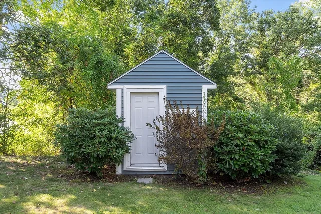 a backyard of a house with plants and large tree