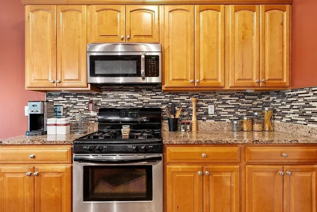 a kitchen with granite countertop a stove top oven microwave and cabinets