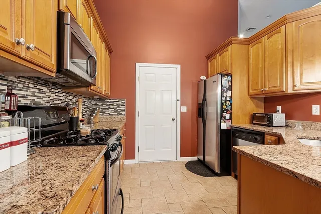 a kitchen with stainless steel appliances granite countertop a stove top oven a sink and a refrigerator