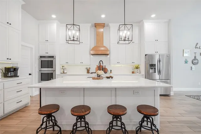 a kitchen with stainless steel appliances granite countertop a sink white cabinets and chairs