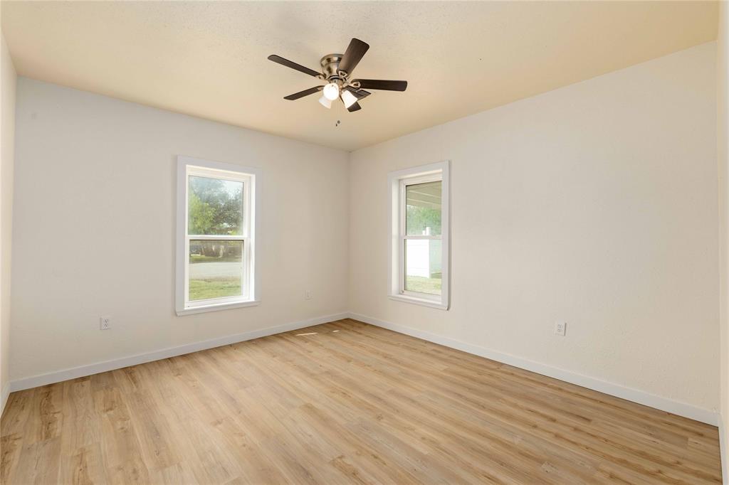 516 South Pecos Street Coleman, TX 76834 - Photo 14 of 32 an empty room with wooden floor fan and windows