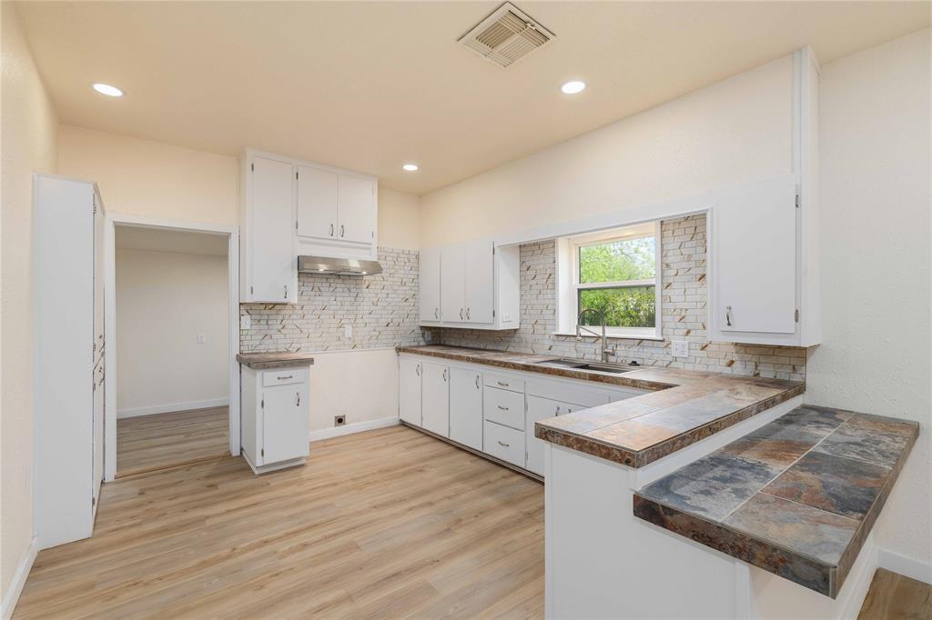 516 South Pecos Street Coleman, TX 76834 - Photo 9 of 32 a kitchen with sink cabinets and wooden floor