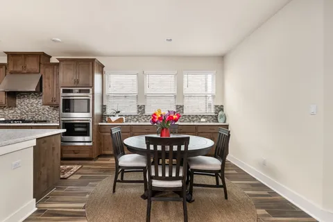 a kitchen with a dining table chairs stainless steel appliances and cabinets