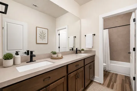 a bathroom with a double vanity sink mirror and shower