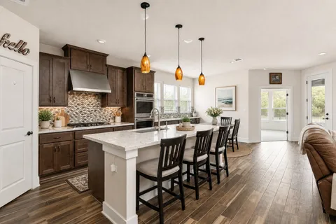 a kitchen with stainless steel appliances granite countertop a table chairs stove and wooden floor