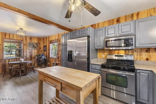 a kitchen with stainless steel appliances granite countertop a refrigerator a sink dishwasher a dining table and chairs with wooden floor