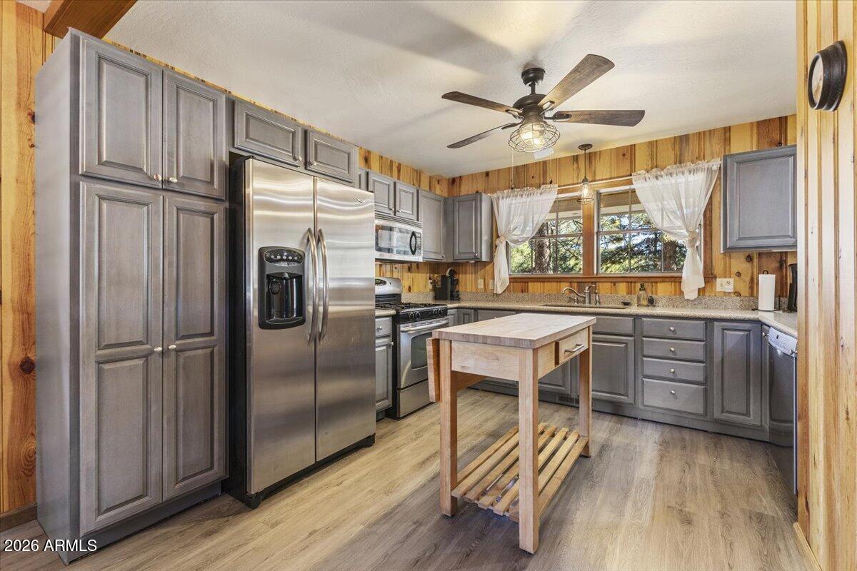 24 County Road 2065 Alpine, AZ 85920 - Photo 9 of 32 a kitchen with stainless steel appliances a refrigerator a stove a sink and white cabinets with wooden floor