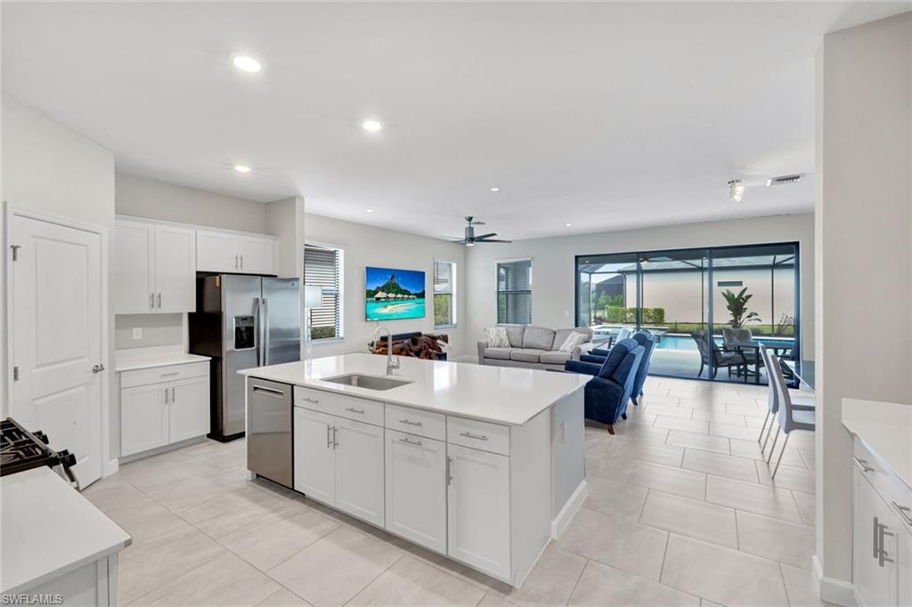 18298 Ridgeline Drive Estero, FL 33928 - Photo 17 of 49 Kitchen with white cabinets, a center island with sink, dishwasher, ceiling fan, and open floor plan