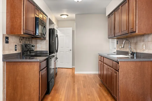 a kitchen with stainless steel appliances granite countertop a refrigerator a sink dishwasher a stove with wooden cabinets and floor