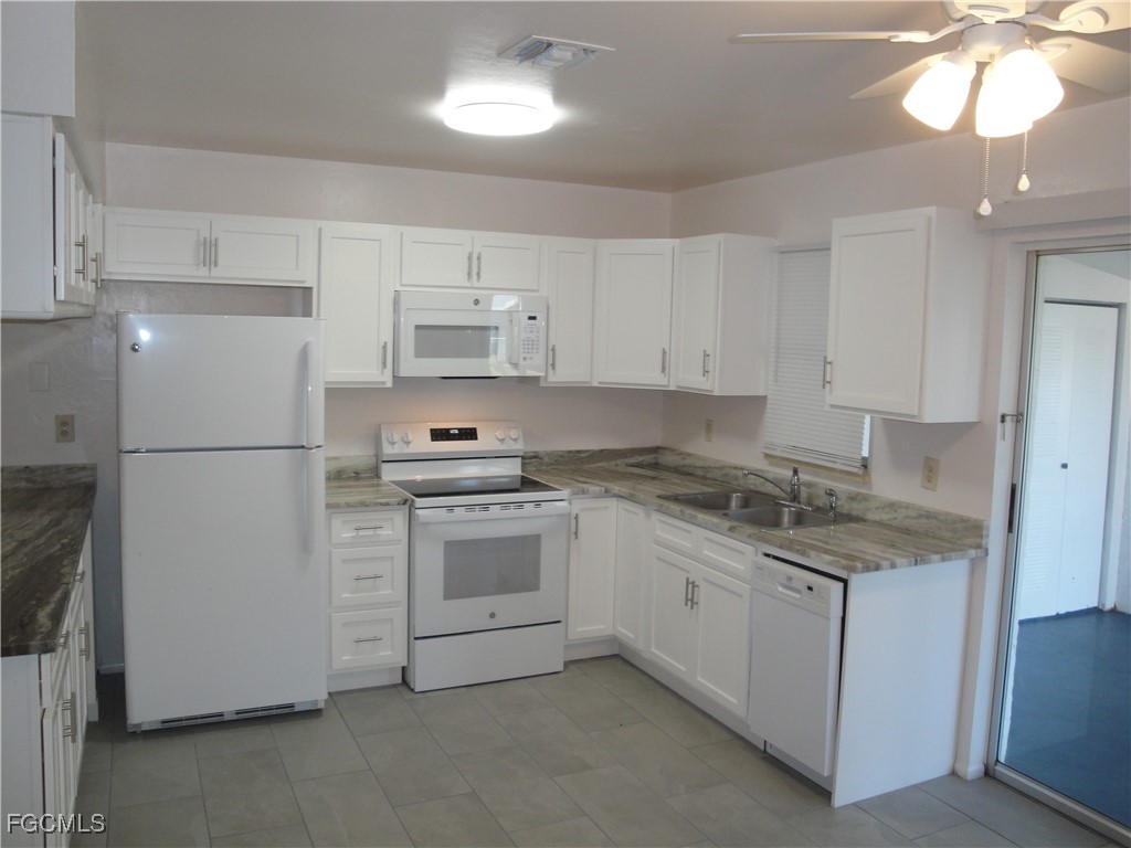 a kitchen with stainless steel appliances granite countertop a refrigerator a stove a sink and white cabinets