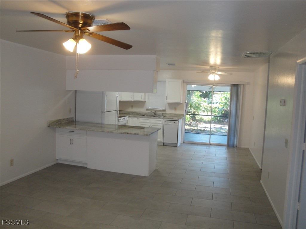 7487 Mellon Road Fort Myers, FL 33967 - Photo 2 of 10 a kitchen with a refrigerator and white cabinets