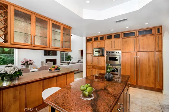 a dinning room with stainless steel appliances granite countertop a dining table chairs and chandelier
