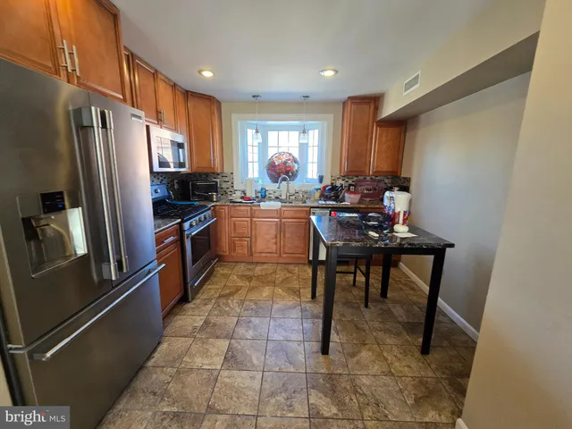 a kitchen with stainless steel appliances granite countertop a refrigerator and a stove top oven