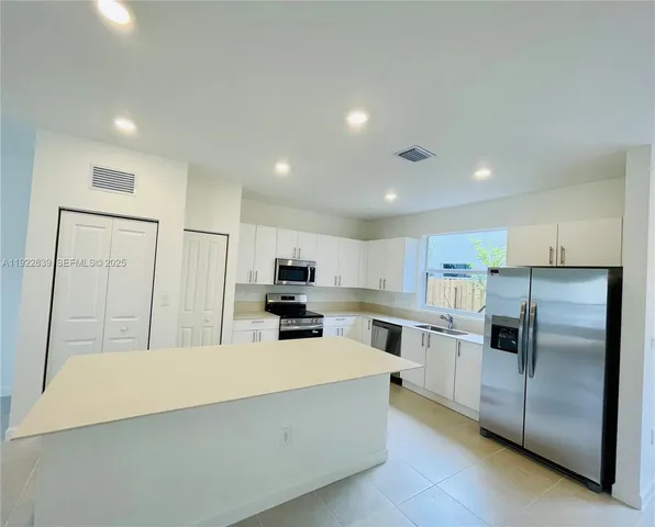 a kitchen with kitchen island a refrigerator sink and cabinets