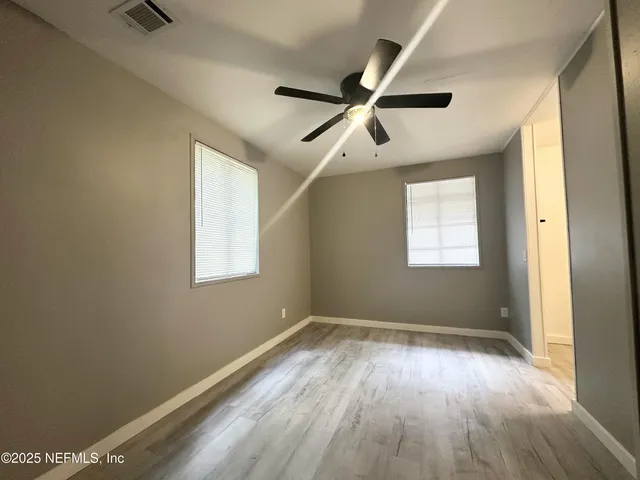 a view of empty room with wooden floor and fan