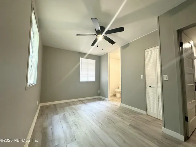 a view of empty room with wooden floor and fan