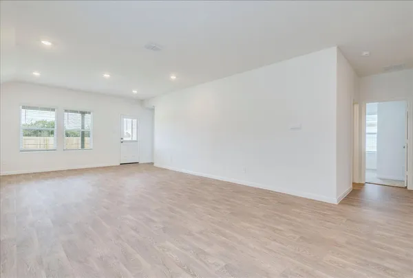 a view of an empty room with wooden floor and windows