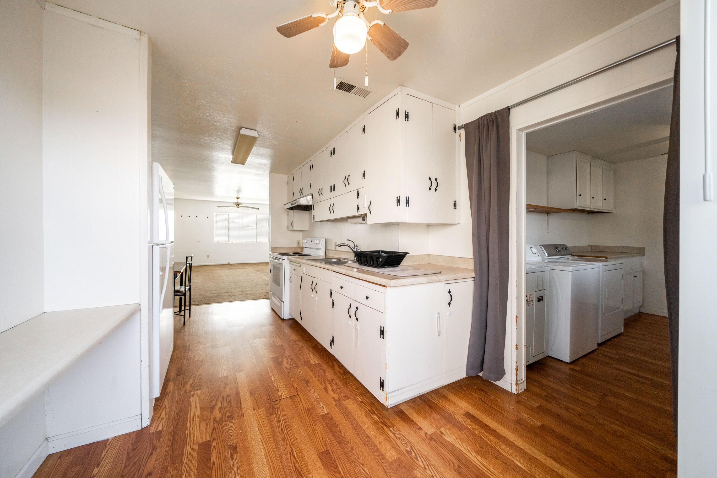 240 Kimball Road Red Bluff, CA 96080 - Photo 15 of 56 a kitchen with white cabinets a sink dishwasher and a stove with wooden floor