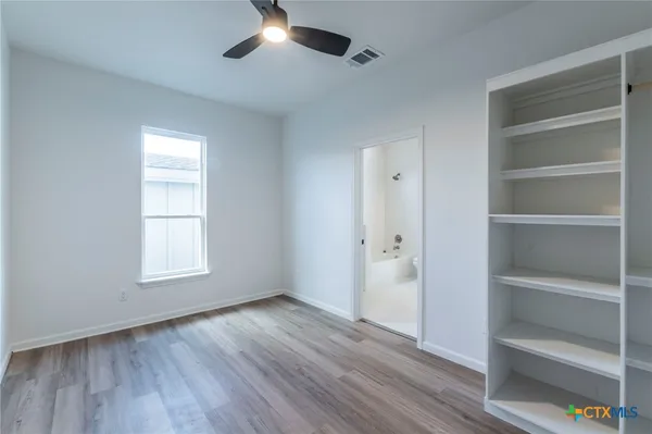 a view of an empty room with a window and wooden floor