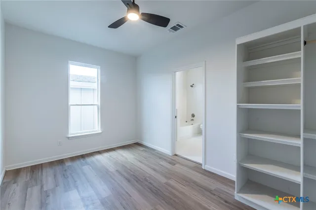 a view of an empty room with a window and wooden floor