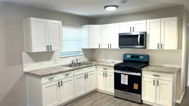 a kitchen with granite countertop a sink and steel appliances