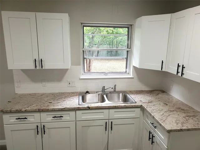 a kitchen with granite countertop white cabinets and a sink