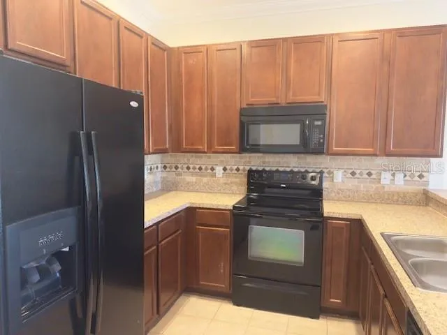 a kitchen with granite countertop a refrigerator stove and cabinets