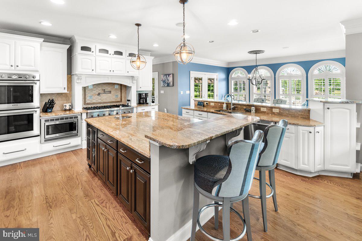 8170 Hollow Road Middletown, MD 21769 - Photo 11 of 67 a kitchen with stainless steel appliances granite countertop a stove a sink dishwasher a microwave oven with a dining table and chairs with wooden floor