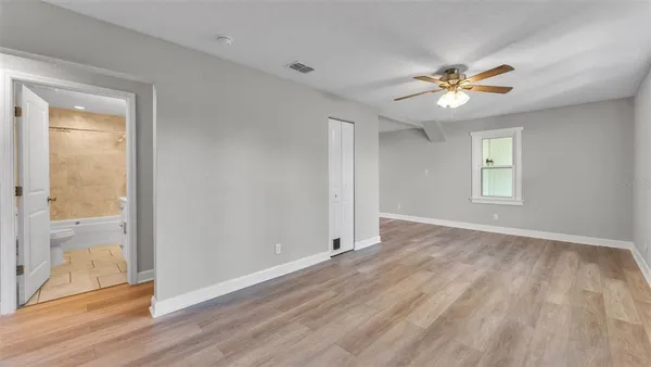 a view of empty room with wooden floor and fan
