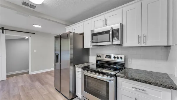 a kitchen with stainless steel appliances granite countertop white cabinets and a stove top oven