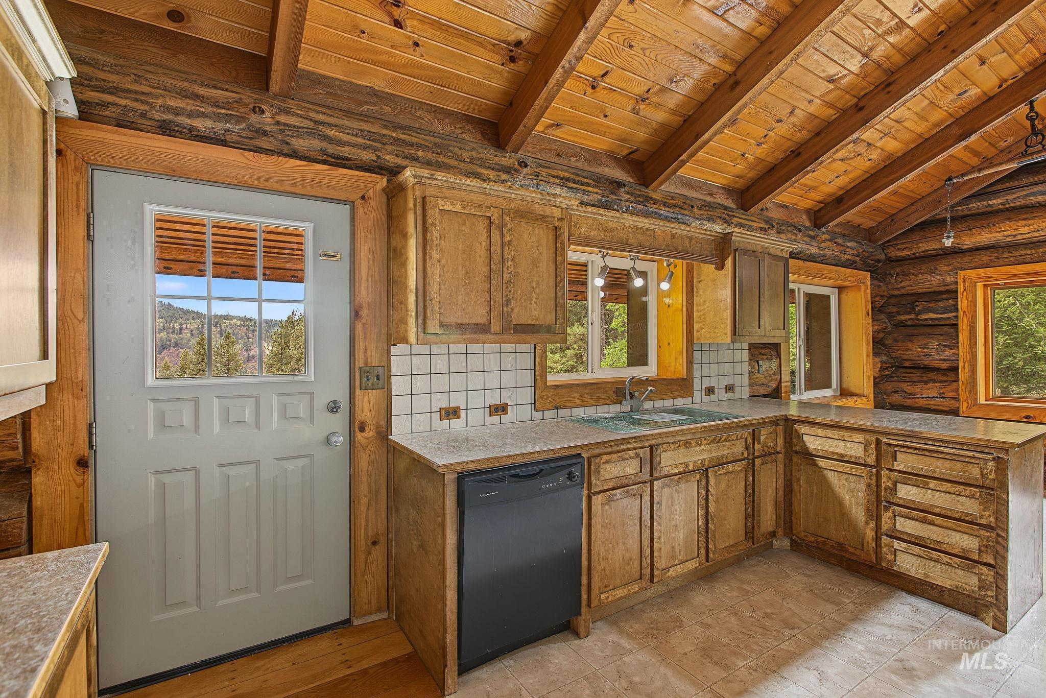 2926 Wells Bench Road Orofino, ID 83544 - Photo 16 of 48 Exposed log walls, natural wood-finish ceiling, wood-finish cabinetry, tile flooring, and a built-in dishwasher