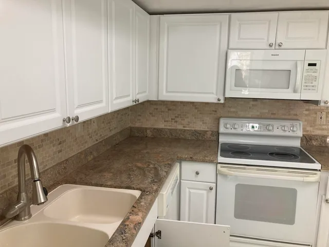 a kitchen with white cabinets and white appliances
