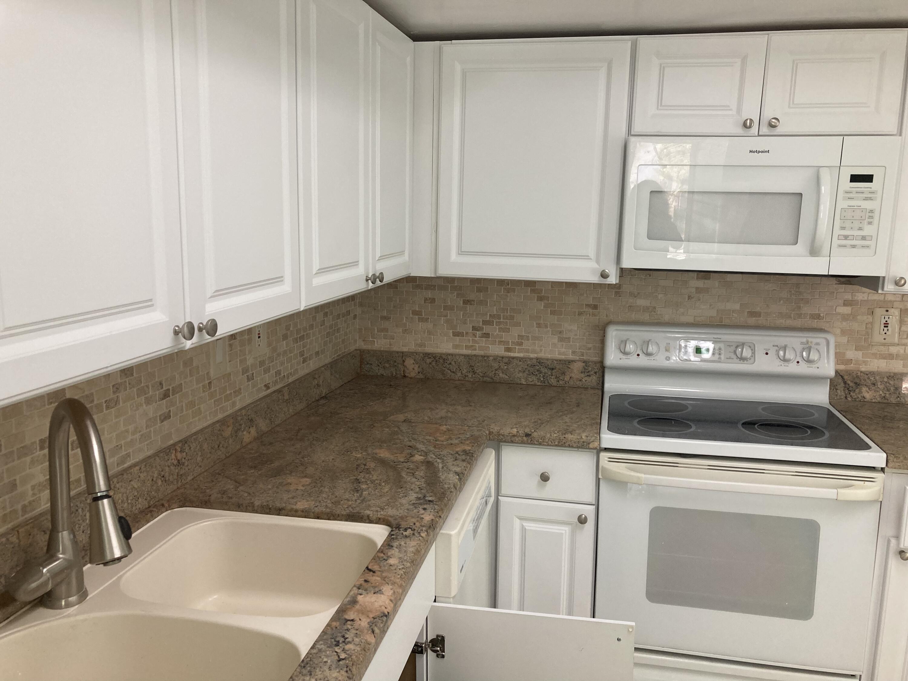 11811 Ave Of The PGA, Unit 21C Palm Beach Gardens, FL 33418 - Photo 19 of 30 a kitchen with white cabinets and white appliances