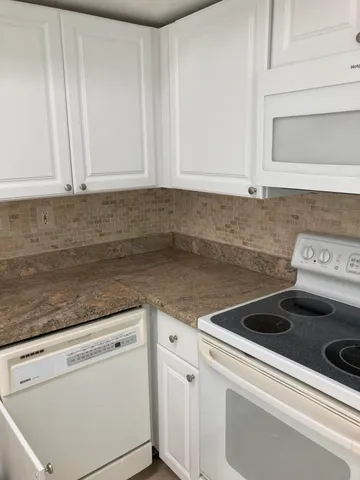 a kitchen with granite countertop white cabinets and white appliances