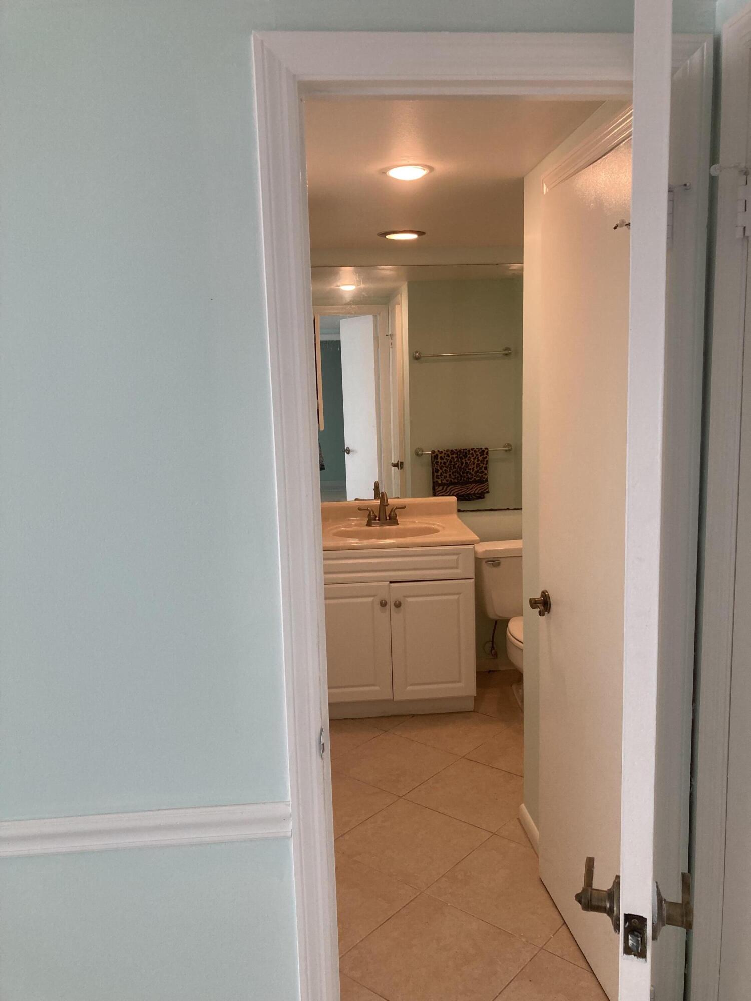 11811 Ave Of The PGA, Unit 21C Palm Beach Gardens, FL 33418 - Photo 23 of 30 a bathroom with a sink a toilet and mirror