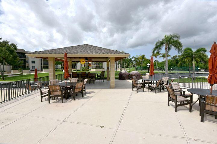 11811 Ave Of The PGA, Unit 21C Palm Beach Gardens, FL 33418 - Photo 3 of 30 a view of a patio with dining table and chairs with a small yard
