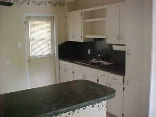 a kitchen with granite countertop white cabinets and black appliances