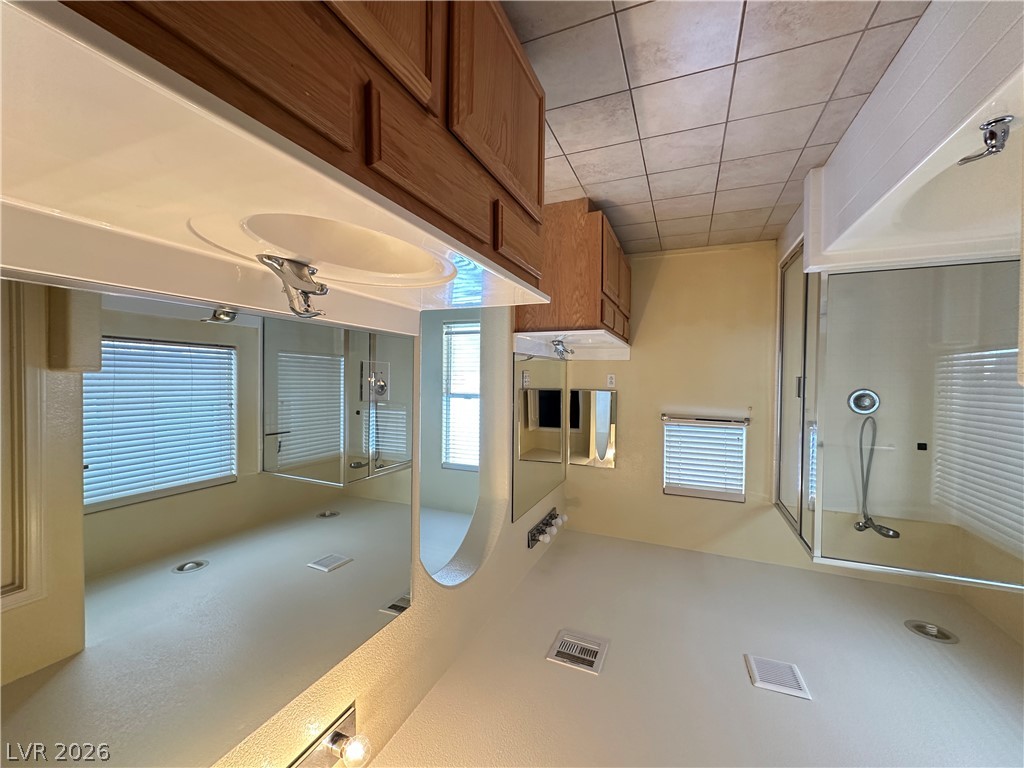 9032 Rutherford Grove Street Las Vegas, NV 89148 - Photo 13 of 24 This primary bathroom features a generous vanity, a glass-enclosed shower, and sleek tile flooring.