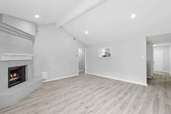 an empty room with wooden floor fireplace and window